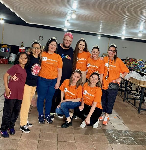 Imagem de alguns integrantes voluntário do Instituto AM com camisetas laranjas abraçados em um abrigo de Porto Alegre.