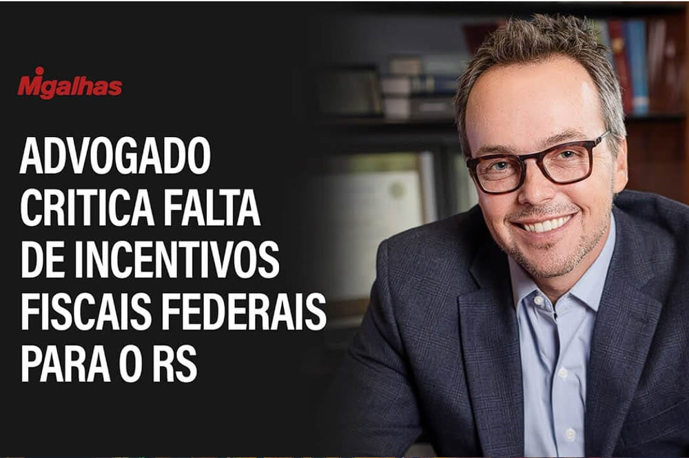 Imagem do sócio fundador Fabio Goldschmidt, um homem branco, sorrindo, de óculos, terno cinza escuro e camisa azul. Ao seu lado está escrito 