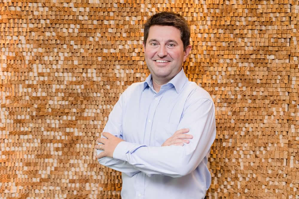 Imagem do sócio do Andrade Maia Jerônimo Goergen, um homem branco, de braços cruzados, sorrindo, usando uma camisa azul clara.